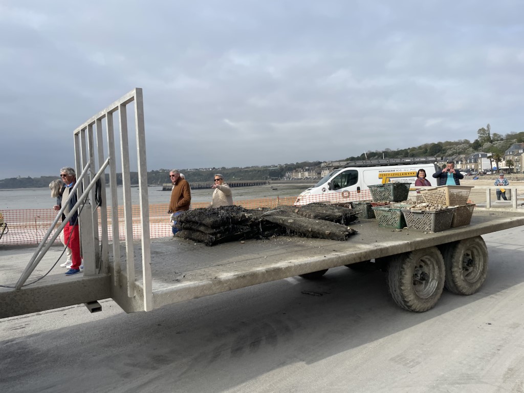 Flat trailer loaded with fresh oyster baskets and mesh bags on the Cancale waterfront, Brittany