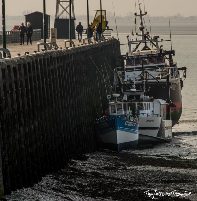 Fishing boats moored at low tide along the stone pier of Cancale harbour, Brittany
