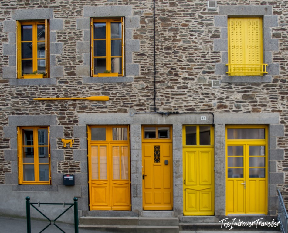 Stone building in Cancale, Brittany, with bright yellow doors and window frames, reflecting the town's coastal charm