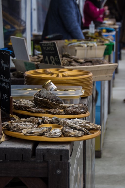 Fresh huitres plates displayed on trays at a Cancale market stall, priced at 18 euros