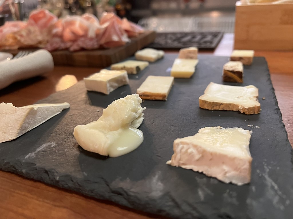 Slate board with assorted French-style cheese slices at Parlor Bologna aperitivo spread