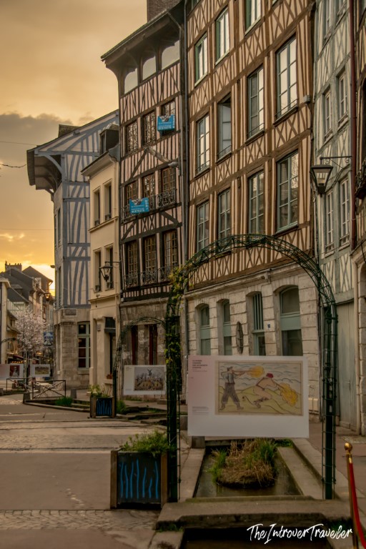 Half-timbered buildings lining a quiet street in Rouen, Normandy, at golden hour