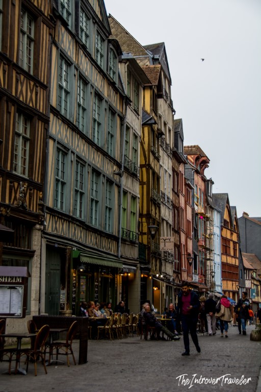 Colorful half-timbered medieval buildings lining a busy street in Rouen, Normandy