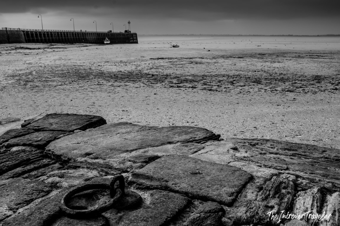 Cancale harbour at low tide, rocky foreshore with mooring ring and pier lighthouse, Brittany