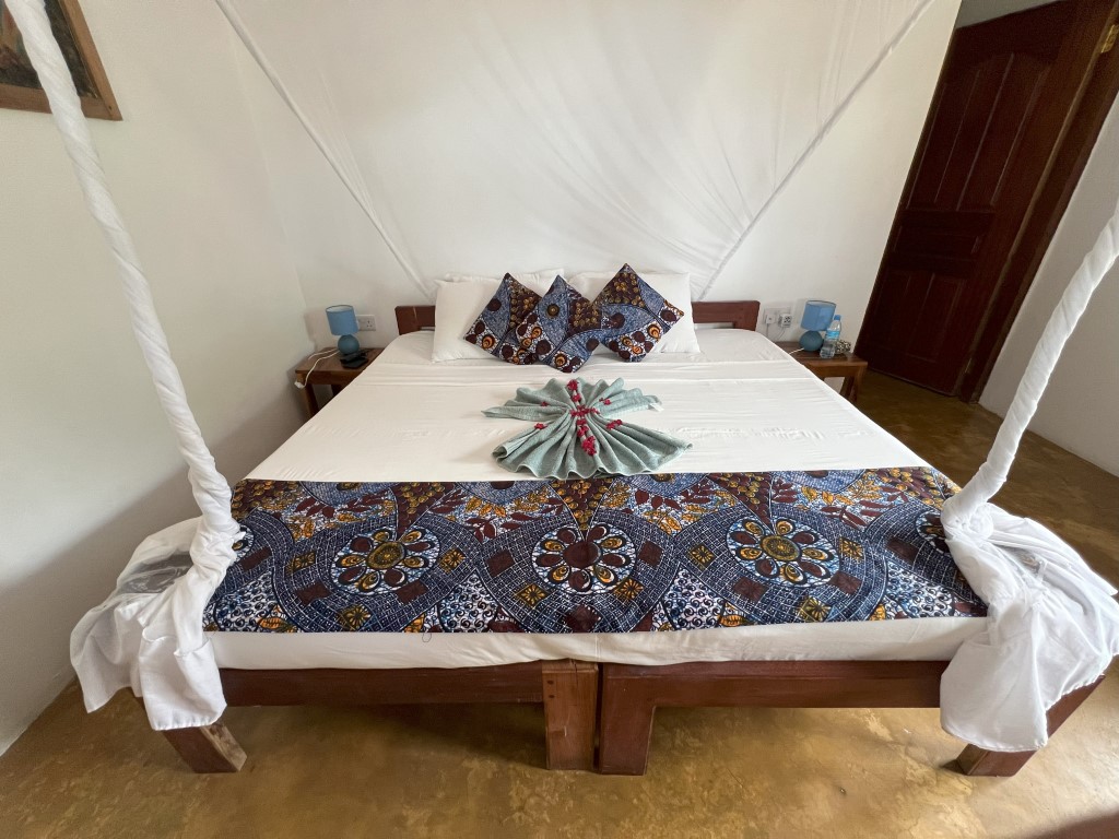 Four-poster bed with African print bedding at a Mafia Island guesthouse, Tanzania
