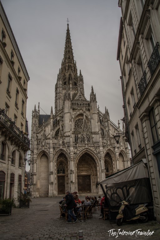 Gothic facade of Eglise Saint-Maclou in Rouen, with a cafe terrace on cobblestones below