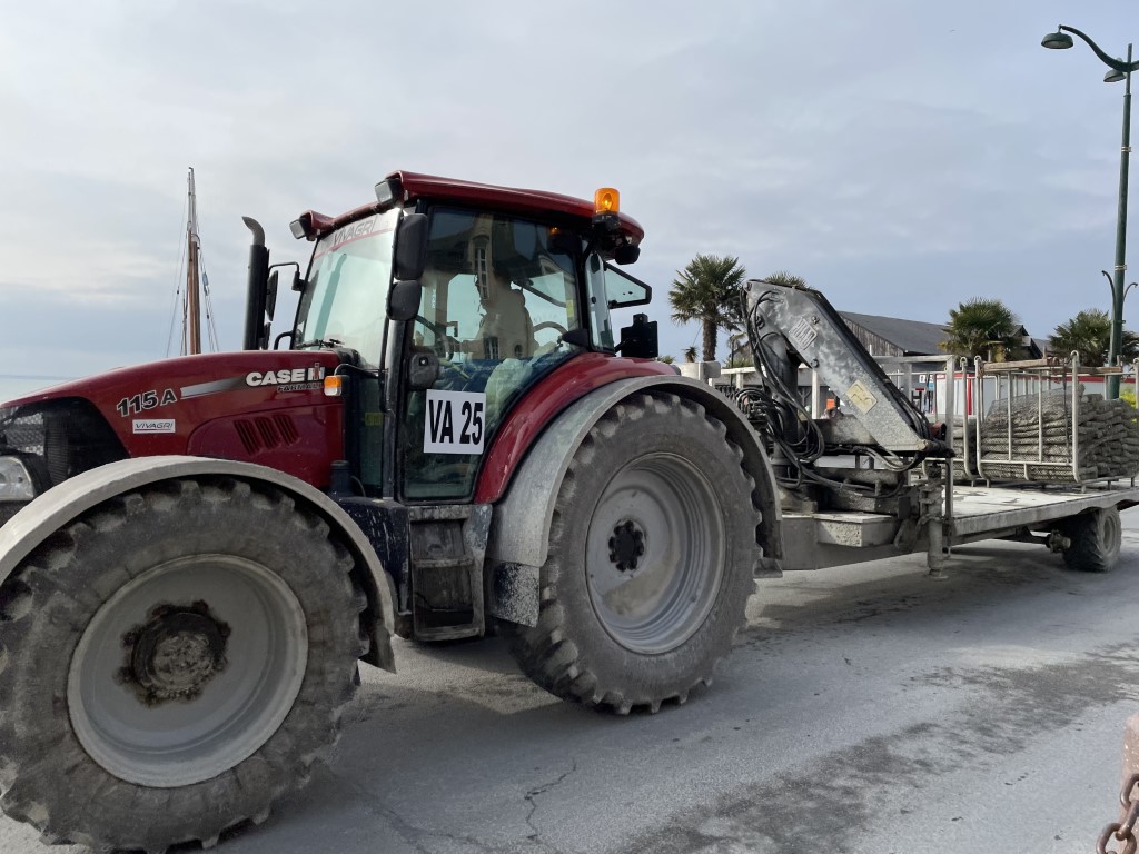 Red Case IH tractor hauling oyster cages at the port of Cancale, Brittany