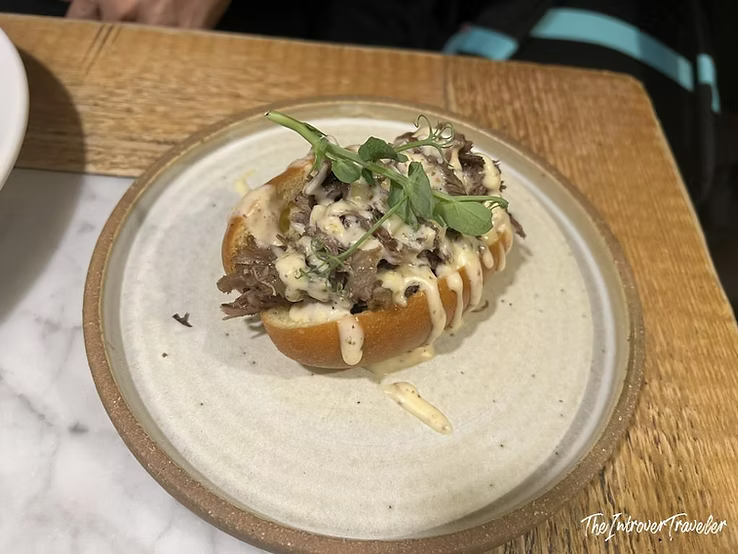 Pulled meat bruschetta with melted cheese and microgreens at Osteria La Quercia, Rome