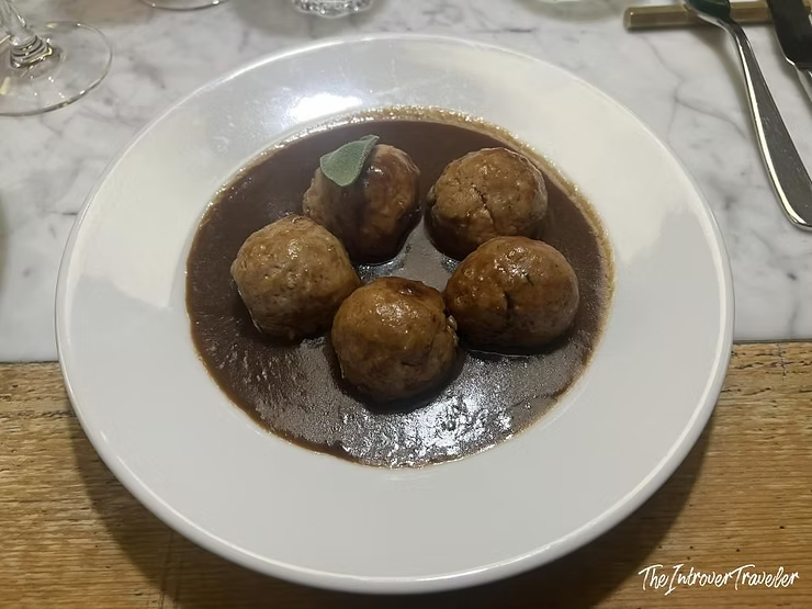 Meatballs in rich dark sauce with a sage leaf, served at Osteria La Quercia in Rome