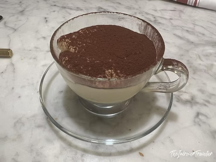 Tiramisu served in a glass cup at Osteria La Quercia, Rome, dusted with cocoa powder
