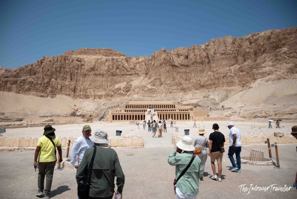 Tourists walking toward the Temple of Hatshepsut, built into the Deir el-Bahari cliffs, Luxor Egypt
