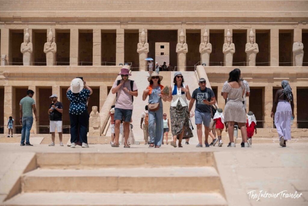 Tourists walking in front of the Osiride statues at the Temple of Hatshepsut, Luxor Egypt