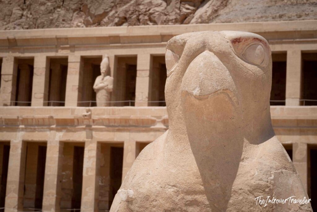 Horus falcon statue at the Temple of Hatshepsut, Luxor, with Osirid pillars behind