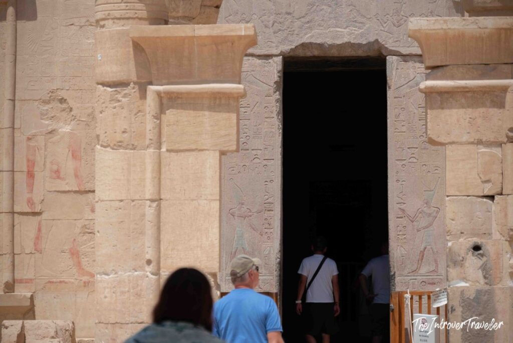 Tourists entering a carved doorway with hieroglyphs at the Temple of Hatshepsut, Deir el-Bahari