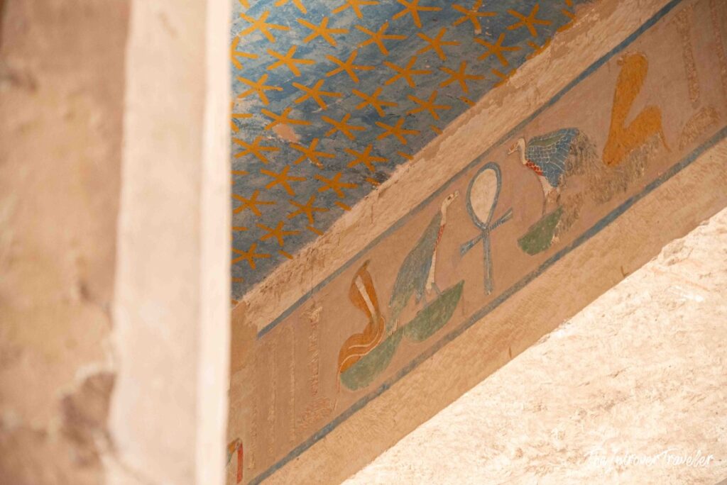 Ancient Egyptian ceiling painting at Hatshepsut temple, showing gold stars, ankh symbol, and sacred birds