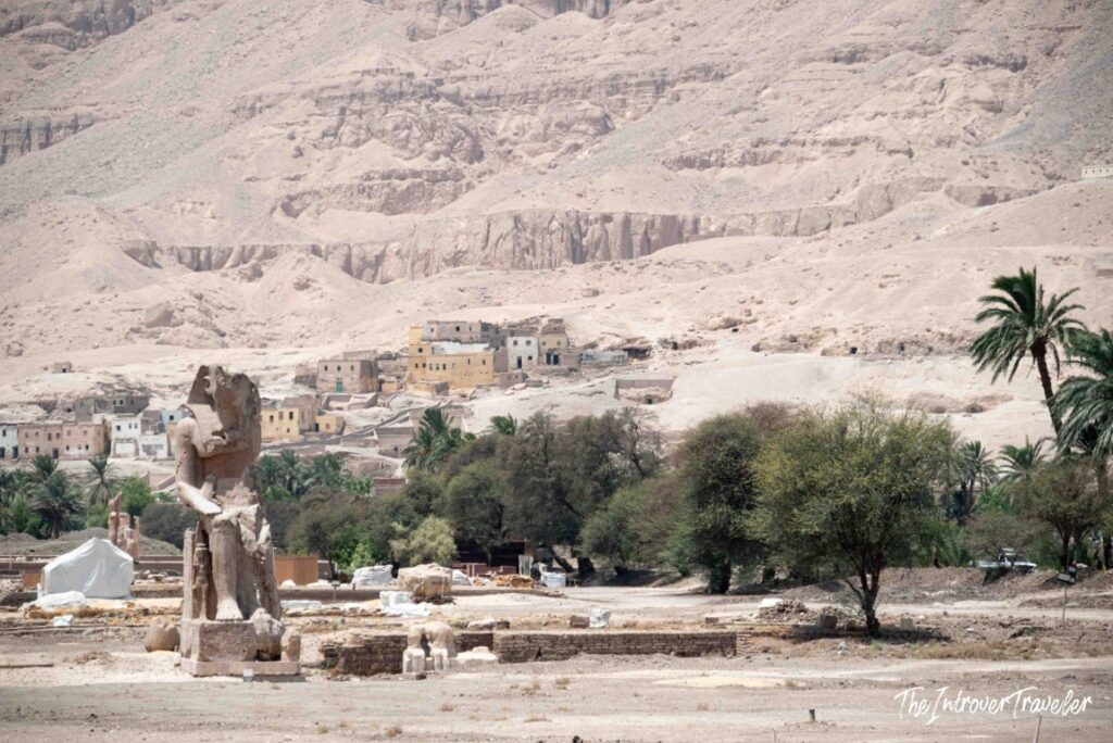 Colossi of Memnon standing before the Theban hills and village near Luxor, Egypt