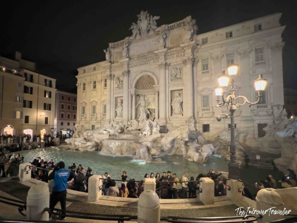 Trevi Fountain at night with visitors at the basin and a steward, Rome