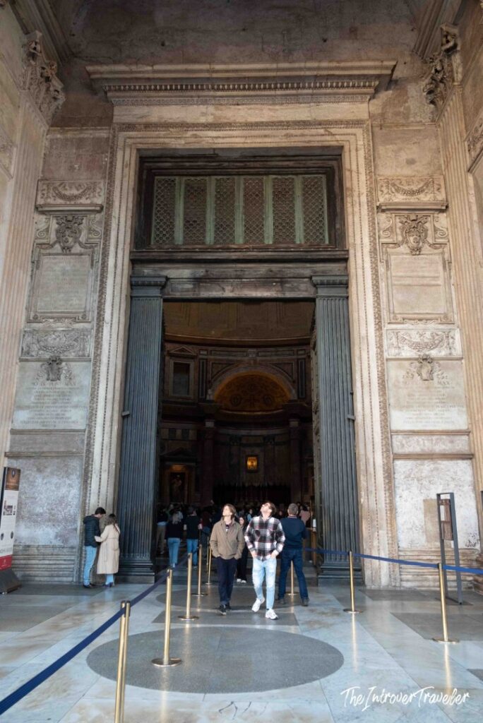 Bronze doors of the Pantheon with visitors looking up as they enter, Rome